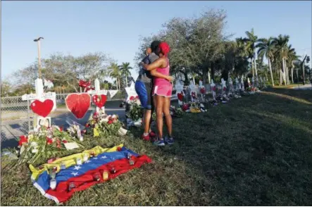  ?? GERALD HERBERT — THE ASSOCIATED PRESS FILE ?? Denyse Christian hugs her son Adin Christian, 16, a student at the school, at a makeshift memorial outside the Marjory Stoneman Douglas High School, where 17 students and faculty were killed in a mass shooting in Parkland, Fla.