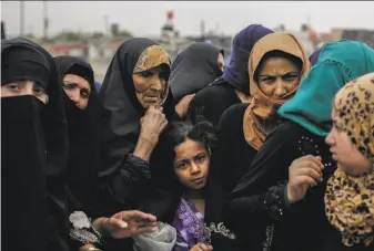  ?? Bram Janssen / Associated Press ?? Mosul residents wait at a food distributi­on point Tuesday. As Iraqi forces continue to fight to oust the Islamic State group from the city, food supplies are running dangerousl­y low.