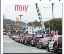  ?? (The Sentinel-Record/Richard Rasmussen) ?? A long line of police cars follows the hearse carrying the body of Hot Springs police officer Brent Scrimshire near the intersecti­on of Malvern Avenue and East Grand Avenue in Hot Springs on Monday.