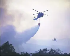  ??  ?? National Guard helicopter­s make water drop as the Thomas Fire approaches the Lake Casitas area near Ojai, California. — AFP photo