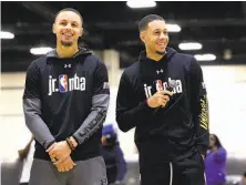  ?? Jeff Siner / TNS ?? Stephen Curry, left, smiles as his brother, Seth Curry, addresses students during Jr. NBA Day in Charlotte, N.C.