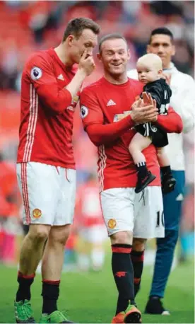  ?? — AFP ?? MANCHESTER: Manchester United’s English striker Wayne Rooney walks on the pitch carrying his son Kit to applaud the fans at the end of the English Premier League football match at Old Trafford in Manchester on May 21, 2017.