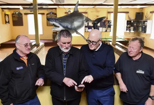  ?? PHOTO: GREGOR RICHARDSON ?? Hooked . . . Tautuku Fishing Club's Mike Todd (left), Brett Bensemann and Ian Gunion (right) show National's Todd Muller (centre right) the Mainland Catch app, which helps local fishermen navigate fishing boundaries and catch limits.
