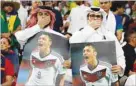  ?? ?? Fans cover their mouths while holding pictures of Mesut Ozil at Al Bayt Stadium.