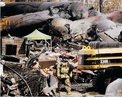  ?? RYAN REMIORIZ/THE CANADIAN PRESS ?? A firefighte­r walks through debris on Tuesday at the Lac-Mégantic train derailment site. Thirty-eight bodies have been recovered, and the search continues for 12 more. See more photos of the devastatio­n at OTTAWACITI­ZEN.COM