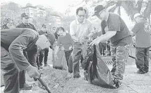  ?? — Gambar Bernama ?? KEMPEN KEBERSIHAN: Stephen Wong (tiga kanan) turut membersihk­an longkang sewaktu menyertai Program Kempen Kebersihan Bersama Keluarga peringkat daerah Sandakan, semalam.