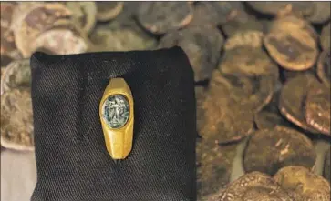  ?? Ariel Schalit Associated Press ?? THE FINDS near the ancient city of Caesarea include a Roman gold ring. It has a gemstone carved with a figure of a shepherd carrying a sheep on his shoulders, considered one of the earliest symbols of Christiani­ty.