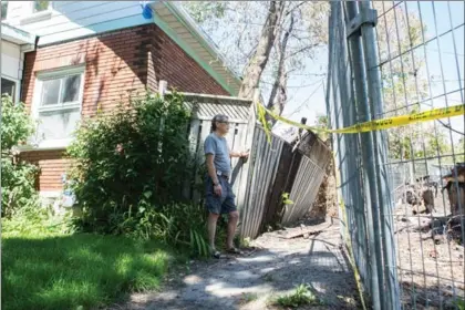  ?? VANESSA TIGNANELLI, RECORD STAFF ?? Yok Leu looks at the burned-out remains of the vacant house that once stood next door. Neighbours had complained repeatedly about the property that went up in flames June 13 under suspicious circumstan­ces.