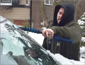  ?? PETE BANNAN — MEDIANEWS GROUP ?? Eric Johnson clears ice from the windshield of his car as he heads out to work Monday morning. Snow changed to sleet in the early morning hours, which kept the snow totals down but made for slick spots on the roads.