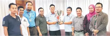  ??  ?? Iskandar (fourth right) hands the tournament trophy to Sebali Chik as secretaria­t members, tournament officials and others look on.