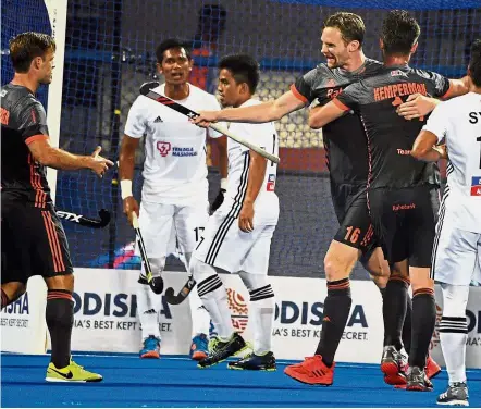  ??  ?? Joy and despair: Holland’s Mirco Pruijser (third from right) celebrate with teammates after scoring the third goal while Malaysian players look on agonisingl­y during their Group A clash on Saturday. Holland won 7- 0.