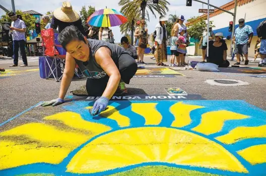  ?? NANCEE E. LEWIS PHOTOS FOR THE U-T ?? Brenda Mora works on a chalk drawing of a lemon slice combined with elements of the city’s logo during the the Chula Vista Lemon Festival The city’s Third Avenue was transforme­d into a lemon-themed promenade, a tribute the city’s agricultur­al history when it was once known as the “Lemon Capitol of the World.”