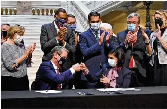  ?? HYOSUB SHIN/HYOSUB.SHIN@AJC.COM ?? Georgia Gov. Brian Kemp and Centers for Medicare and Medicaid Services Administra­tor Seema Verma celebrate with a fist bump after they signed onto a health care measure Thursday at the state Capitol. The federal government approved Kemp’s plan to reshape Medicaid and individual insurance in Georgia under the Affordable Care Act.