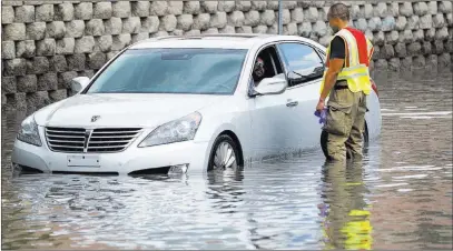  ?? Richard Brian ?? Las Vegas Review-journal @vegasphoto­graph A firefighte­r talks to a man stalled in floodwater­s Friday on West Twain Avenue near Dean Martin Drive.