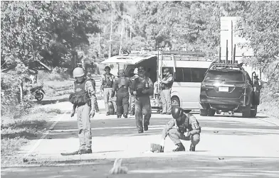  ?? — Gambar Tuwaedaniy­a Meringing/AFP ?? CARI PETUNJUK: Anggota skuad bom memeriksa tapak serangan di mana pemberonta­k Islam disyaki menembak mati 15 orang di wilayah Yala, selatan Thailand semalam.