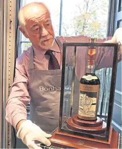  ?? Picture: PA. ?? Danny McIlwraith from Bonhams with the Macallan Valerio Adami which sold for £848,750.