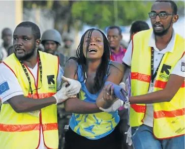  ?? Picture: EPA ?? WITNESS TO HORROR: A traumatise­d woman is escorted from the building at Garissa University in Kenya where she had been held hostage by al-Shabab militants. At least 148 people were killed in the attack on Thursday