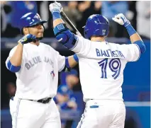  ??  ?? Jays’ Jose Bautista celebrates with teammate Edwin Encarnacio­n after hitting a solo home run in Friday’s game against Tampa Bay Rays.