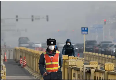  ?? AP file photo ?? A traffic officer wearing a mask patrols near Tiananmen Square in Beijing as smog blankets the Chinese capital in January. Antipollut­ion efforts have helped improve air quality in Beijing.