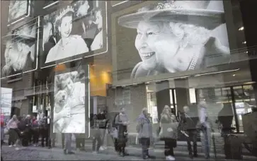  ?? Christophe Ena Associated Press ?? IMAGES of Queen Elizabeth II are on display as people wait to pay their respects on Friday in London. The Metropolit­an Police have brought in 10,000 officers and deployed 1,500 soldiers ahead of Monday’s funeral.