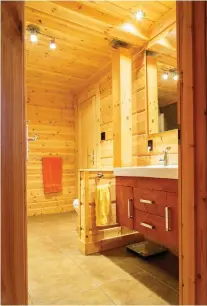  ??  ?? The spacious bathroom looks very much like a sauna room — all in wood with an earth-toned ceramic floor.