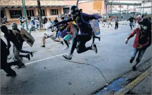  ?? AP PHOTO ?? Anti-government protesters run from advancing Venezuelan Bolivarian National Guard officers on the first day of a 48-hour general strike in protest of government plans to rewrite the constituti­on, in Caracas, Venezuela, Wednesday.