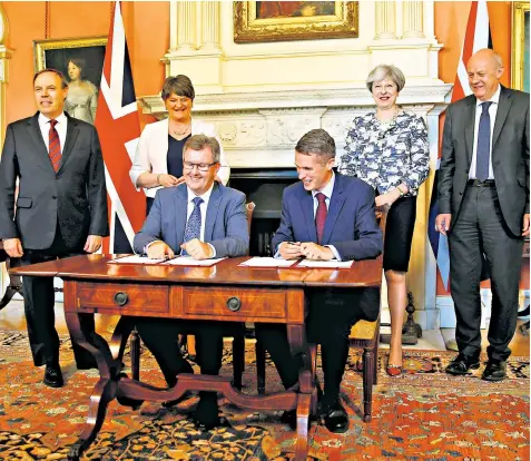  ??  ?? The DUP’S Sir Jeffrey Donaldson, left, and Gavin Williamson, the Chief Whip, sign paperwork after Theresa May and her colleagues met DUP leader Arlene Foster to finalise a deal