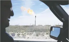  ?? MATTHEW BUSCH/BLOOMBERG FILES ?? A gas flare is seen through the window as a Royal Dutch Shell Plc representa­tive drives near Mentone, Texas, in this 2017 file photo. Sellside analysts are staying bullish despite the volatility in oil and natural gas prices.
