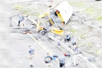  ?? — Reuters photo ?? Police stand near the wreckage of a school bus on Interstate 80 following an accident with a dump truck in Mount Olive Township, New Jersey, US.