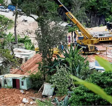  ??  ?? Tragic situation: ( Top) A landslide at the constructi­on site in Jalan Bukit Kukus, Paya Terubong, caused four containers to be covered in mud. — Bernama