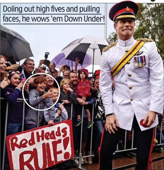  ??  ?? Ginger pride: Ethan Toscan (circled) holding his sign for Harry in Canberra yesterday. Hundreds waited in the rain to see the prince