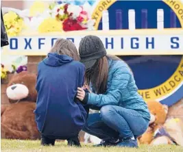  ?? PAUL SANCYA/AP ?? Mourners share their grief Wednesday at a makeshift memorial at Oxford High School in Michigan. Oakland County authoritie­s did not reveal a motive in the shooting.