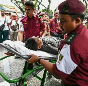  ??  ?? Quick to respond: Medics evacuating a protester who fainted during the rally. — AFP