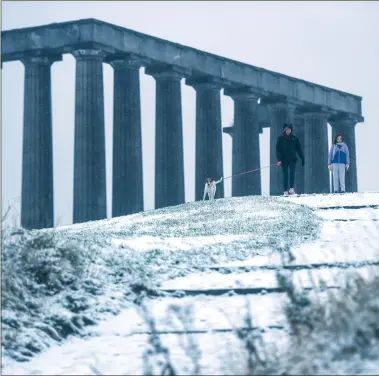  ?? ?? Dog walkers on Calton Hill, in Edinburgh, after areas across the country were affected by snow