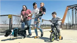  ?? ?? ABOVE: From left, Emerson Howard and dog Dixie enjoy a walk along with Destiny Porter and her children, 2-year old Merrick Mercer and 4-year old Maxton Mercer on Wednesday at a bridge connecting trail systems in Muncie, Ind.