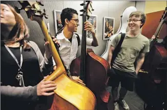  ??  ?? ORCHESTRA members Sukyung Chun, left, who plays the bass, Marlon Martinez, who plays the bass, and Allan Steele, who plays the cello, fill an elevator after rehearsal at the Colburn School.