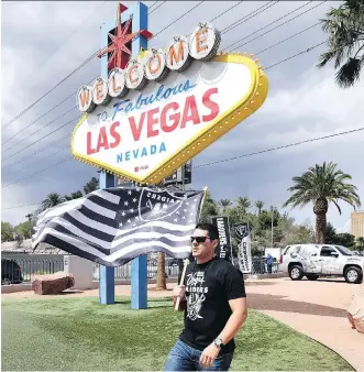  ?? ETHAN MILLER/GETTY IMAGES ?? Matt Gutierrez carries a Raiders flag in front of the “Welcome to Fabulous Las Vegas” sign after NFL owners voted 31-1 Monday to approve the franchise’s relocation from Oakland by 2020.