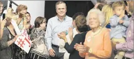  ?? David Goldman ?? JEB BUSH, center, takes the stage at a college in Miami to announce his run for president. “It’s nobody’s turn,” he said, dismissing talk of dynastic succession.