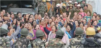  ?? — AFP ?? Police personnel stop Gorkha Janmukti Morcha supporters following a raid at the GJM office in Darjeeling on Thursday.