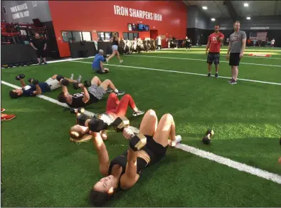  ?? (NWA Democrat-Gazette/Flip Putthoff) ?? Coaches Brandon Mallow (standing left) and Jim Ed Reed conduct a group workout last week at D1 Training in Rogers.