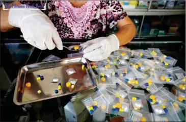  ?? PHA LINA ?? A woman packs individual pills including antibiotic­s into medication packages at a pharmacy in Phnom Penh in 2014.