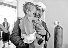  ?? — AFP photo ?? File photo shows a Yemeni man carrying his child who is suffering from malnutriti­on into a treatment centre at a hospital in the capital Sanaa.