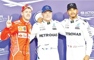  ?? — AFP photo ?? Mercedes' Finnish driver Valtteri Bottas (C) pose with his teammate British driver Lewis Hamilton (R) and Ferrari's German driver Sebastian Vettel at the end of the qualifying session ahead of the Abu Dhabi Formula One Grand Prix at the Yas Marina...