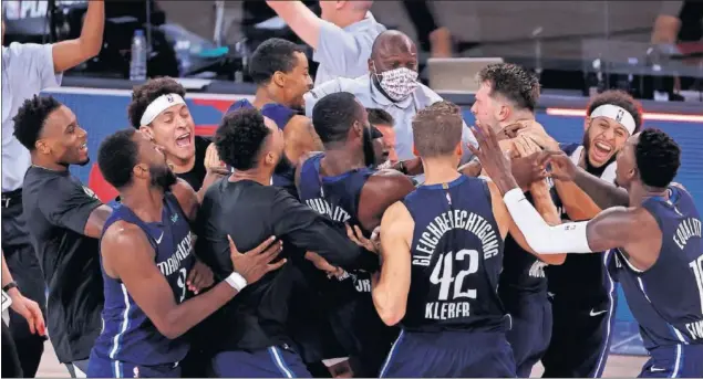  ??  ?? Los jugadores de los Mavericks rodean a Luka Doncic después del triple decisivo con el que el esloveno fulminó a los Clippers en el último segundo de la prórroga.