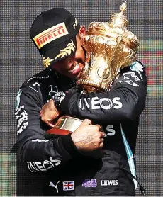  ?? — AFP photo ?? Hamilton holds the trophy on the podium after the Formula One British Grand Prix motor race at Silverston­e motor racing circuit in Silverston­e, central England.