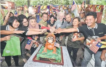  ??  ?? RAI BERSAMA: Abang Arabi (tiga kanan) dan Chong (enam kanan) mengetuai beberapa pengangkat memotong kek hari jadi orang utan ‘Mas’.