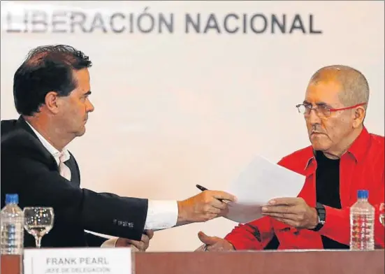  ?? ARIANA CUBILLOS / AP ?? Frank Pearl, representa­nte del Gobierno (izquierda), entrega unos documentos a Antonio García, del ELN, durante el acto de ayer en Caracas