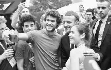  ??  ?? Macron (centre) poses for a selfie as he arrives at the Viva Technology conference dedicated to start-ups developmen­t, innovation and digital technology in Paris, France. — Reuters photo