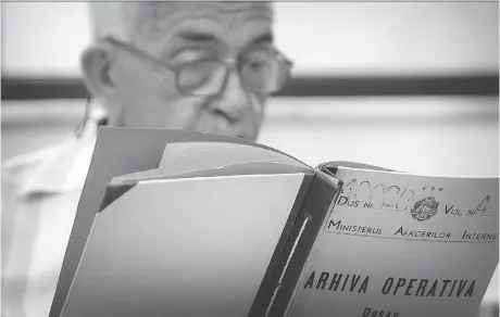  ?? THE ASSOCIATED PRESS ?? A man who refused to be identified by name reads a communist-era secret police file in Bucharest, Romania. The country’s secret police kept a large file on Katherine Verdery, who recounts in her memoir that she was doing research on Romanian village life in the 1970s and ’80s.