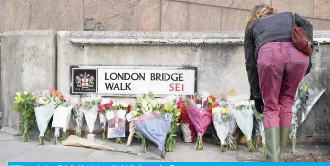  ??  ?? LONDON: A woman places flowers with other floral tributes close to London Bridge in the City of London yesterday.